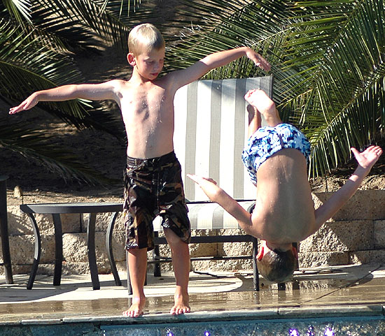 Kids at play at the ledge at the deep end of the pool -