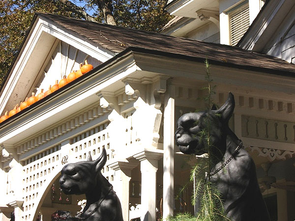 Georgia porch, Halloween 2006 - This house has pumpkins on the gable of an arched lattice porch.  The sinister cats were props at a Kiss concert but have been put to work every Halloween for at least a decade. Usually little children must wait to trick or treat here because the cats are just too scary.